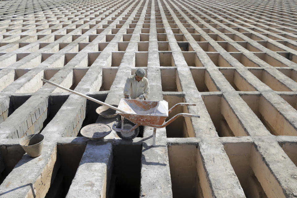 A cemetery worker prepares new graves at the Behesht-e-Zahra cemetery on the outskirts of the Iranian capital, Tehran, Iran, Sunday, Nov. 1, 2020. The cemetery is one of the world's largest with 1.6 million people buried on its grounds, stretching across more than five square kilometers (two square miles), but it is struggling to keep up with the coronavirus pandemic ravaging the country. (AP Photo/Ebrahim Noroozi)