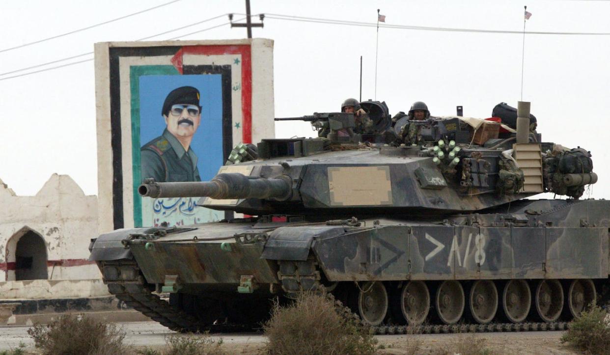 A U.S. tank moves past a painting of Saddam Hussein in March 2003 in Nasiriyah, Iraq. <a href="https://media.gettyimages.com/id/1869040/photo/u-s-marines-battle-for-control-of-nasiriyah.jpg?s=1024x1024&w=gi&k=20&c=TcKau_YTfvg31IRCBIvpscnnoJOuVybF5jCvW7fRYA4=" rel="nofollow noopener" target="_blank" data-ylk="slk:Joe Raedle/Getty Images;elm:context_link;itc:0;sec:content-canvas" class="link ">Joe Raedle/Getty Images</a>