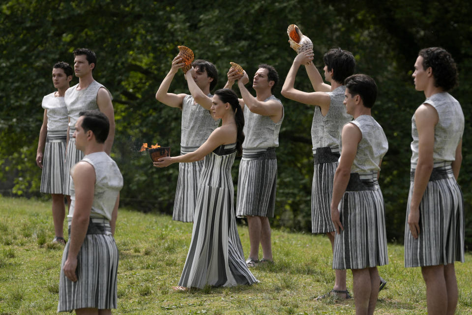 Actress Mary Mina, playing high priestess, center, carries a ceramic pot with the flame during the official ceremony of the flame lighting for the Paris Olympics, at the Ancient Olympia site, Greece, Tuesday, April 16, 2024. The flame will be carried through Greece for 11 days before being handed over to Paris organizers on April 26. (AP Photo/Thanassis Stavrakis)