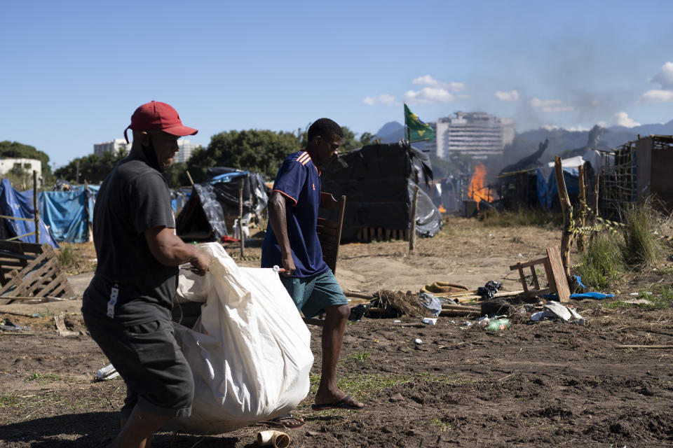 People carry their belongings after they were evicted from land designated for a Petrobras refinery, at a settlement coined the "First of May Refugee Camp," named for the date people moved in setting up tents and shacks, in Itaguai, Rio de Janeiro state, Brazil, Thursday, July 1, 2021, amid the new coronavirus pandemic. (AP Photo/Silvia Izquierdo)