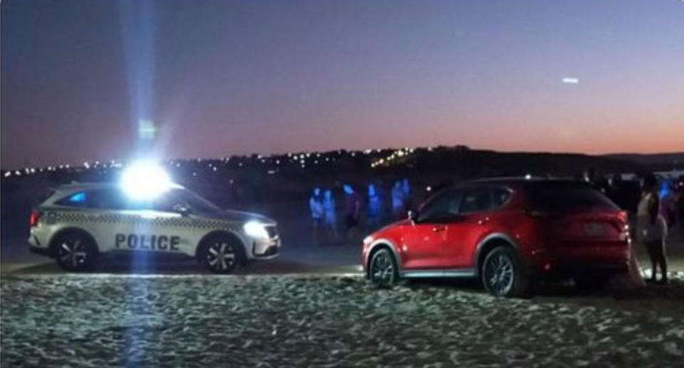 Police car and red Mazda on Moana beach, South Australia. 