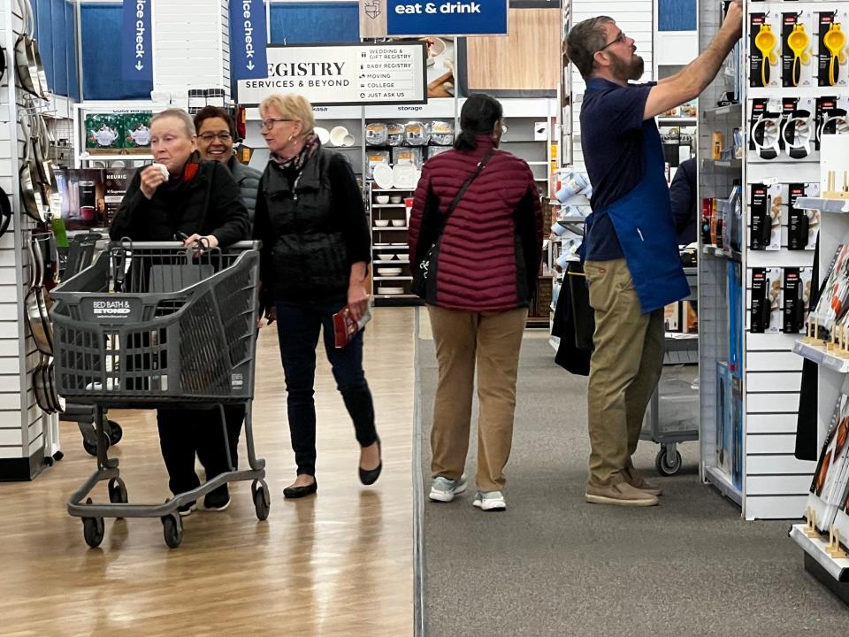 Shoppers push a cart while an employee works at a Bed Bath & Beyond store