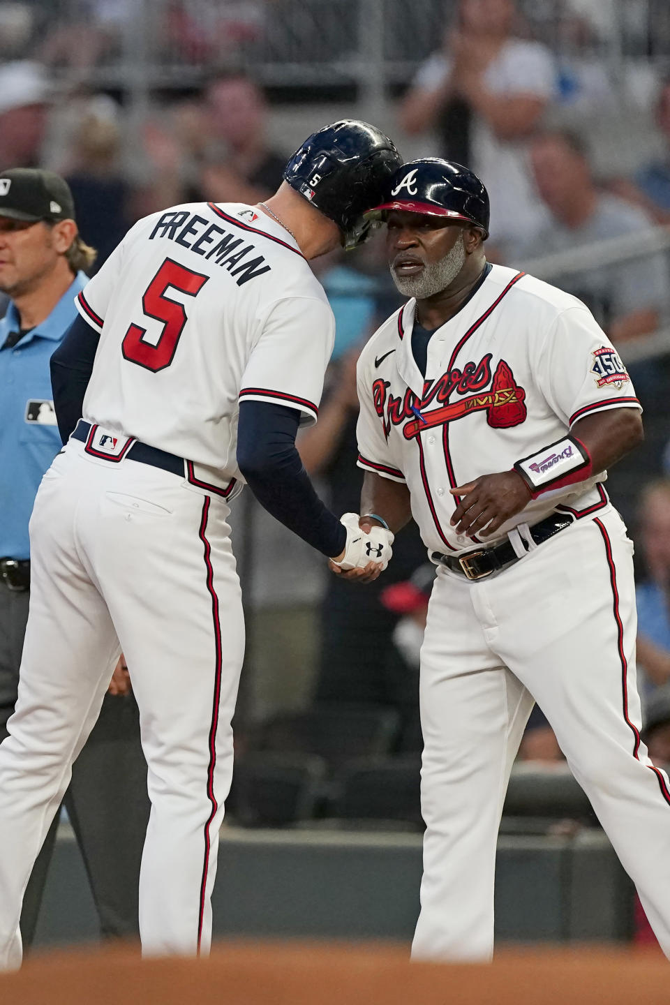 Atlanta Braves first baseman Freddie Freeman (5) touches helmets with first base coach Eric Young Sr. (2) after an RBI single in the first inning of a baseball game against the Colorado Rockies Tuesday, Sept. 14, 2021, in Atlanta. (AP Photo/John Bazemore)