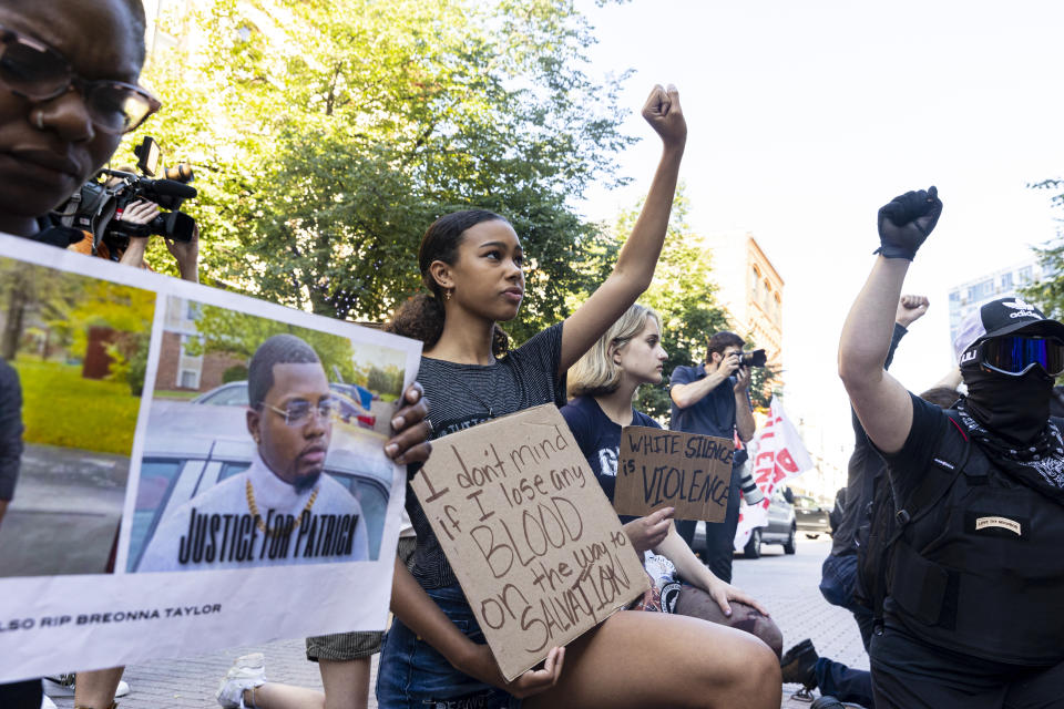 Naiara Tamminga, 13, holds a fist in the air during a moment of silence for Patrick Lyoya outside of Grand Rapids Police Department in Grand Rapids, Mich. on Thursday, June 9, 2022. A prosecutor filed a second-degree murder charge Thursday against the Michigan police officer who killed Patrick Lyoya, a Black man who was on the ground when he was shot in the back of the head following an intense physical struggle recorded on a bystander's phone. (Joel Bissell/The Grand Rapids Press via AP)