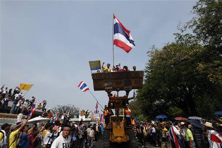 Anti-government protesters celebrate on a front loader used to knock down a concrete barricade outside the Government House in Bangkok December 9, 2013. Thai Prime Minister Yingluck Shinawatra dissolved parliament on Monday and called a snap election, but anti-government protest leaders pressed ahead with mass demonstrations seeking to install an unelected body to run the country. REUTERS/Kerek Wongsa