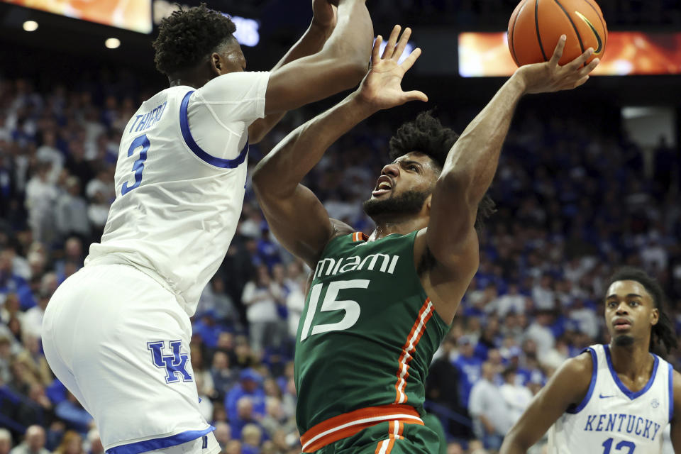 Miami's Norchad Omier (15) shoots while pressured by Kentucky's Adou Thiero, left, during the first half of an NCAA college basketball game in Lexington, Ky., Tuesday, Nov. 28, 2023. Kentucky won 95-73. (AP Photo/James Crisp)