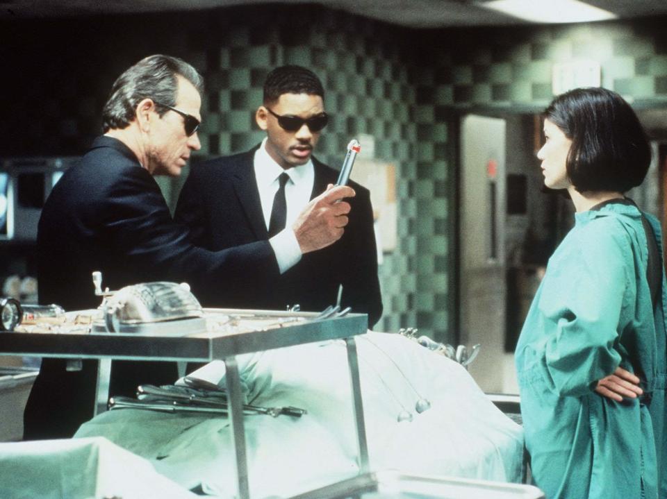 Tommy Lee Jones and Will Smith standing across from Linda Fiorentino