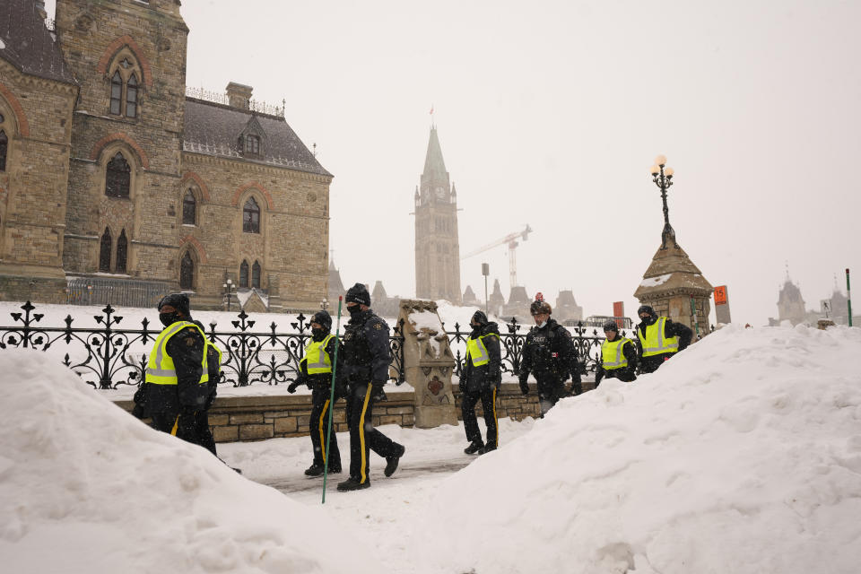 Police officers walk pass the Parliament buildings in Ottawa on Sunday, Feb. 20, 2022. A protest, which was first aimed at a COVID-19 vaccine mandate for cross-border truckers but also encompassed fury over the range of COVID-19 restrictions. (Adrian Wyld/The Canadian Press via AP)