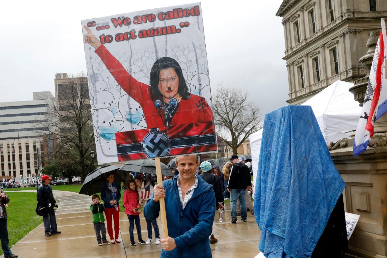 A protestor holds a sign with Michigan Gov. Gretchen Whitmer depicted as Adolph Hitler