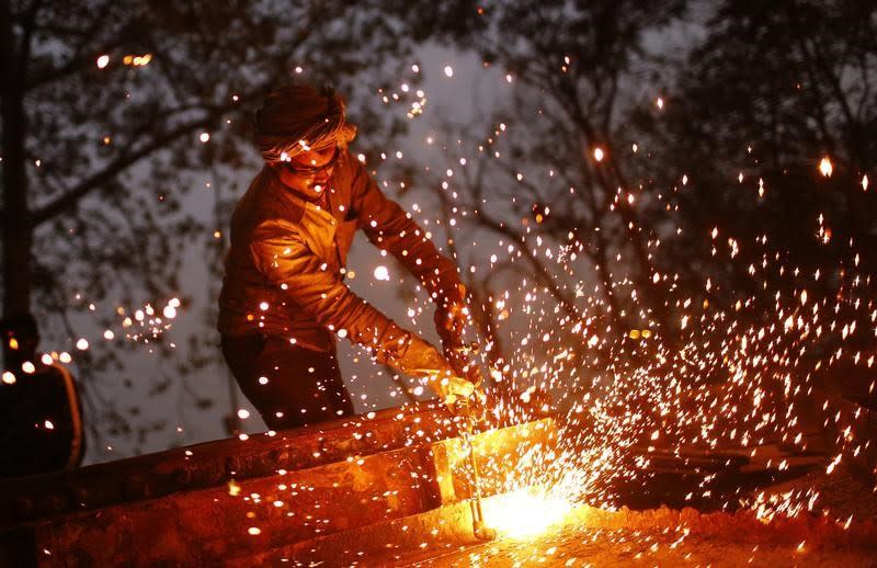 A worker uses a welding torch to weld an iron machine at the construction site of a flyover in New Delhi January 6, 2014. REUTERS/Anindito Mukherjee
