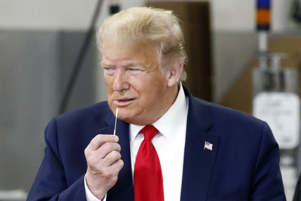 El presidente Donald Trump sostiene un hisopo cerca de su nariz mientras recorre las instalaciones de Puritan Medical Products, una compañía que los fabrica, el viernes 5 de junio de 2020, en Guilford, Maine. (AP Foto/Patrick Semansky)