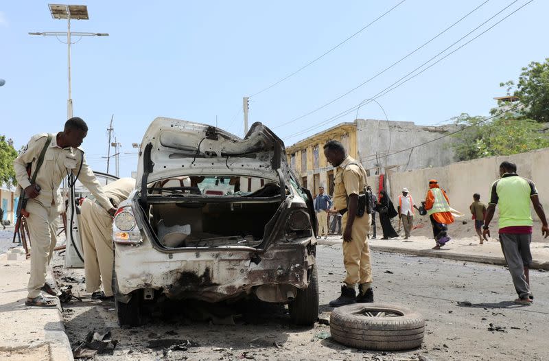 Policemen assess the wreckage of a car at the scene of a bomb explosion at the Maka al-Mukarama street in Mogadishu