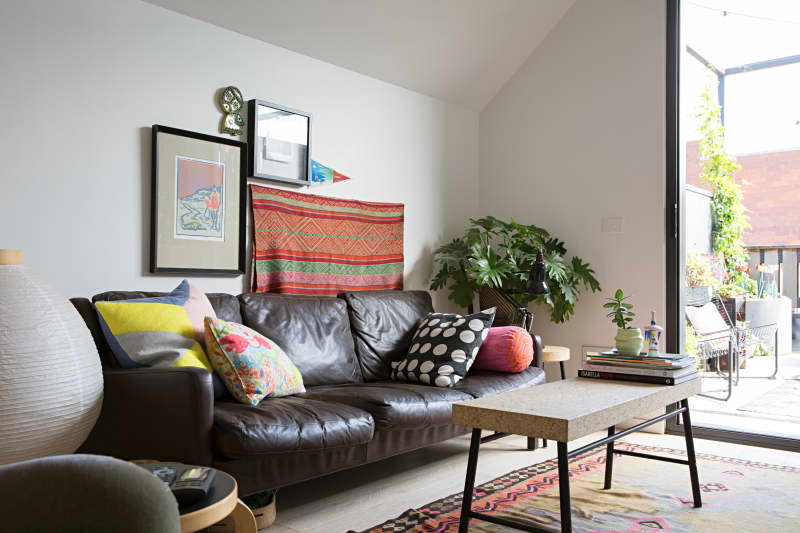 brown leather couch, simple  terrazzo rectangle coffee table, large door to outdoor place, colorful throw pillows