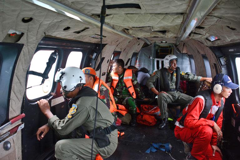 Crew members of an Indonesian Air Force Super Puma helicopter look out the windows during search operations for victims of AirAsia Flight QZ8501 over the Java Sea on January 1, 2015