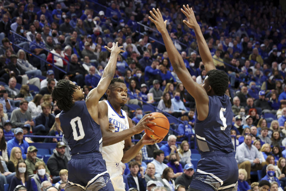 Kentucky's Oscar Tshiebwe, center, looks for an opening between North Florida's Emmanuel Adedoyin (0) and Dorian James (5) during the first half of an NCAA college basketball game in Lexington, Ky., Friday, Nov. 26, 2021. (AP Photo/James Crisp)