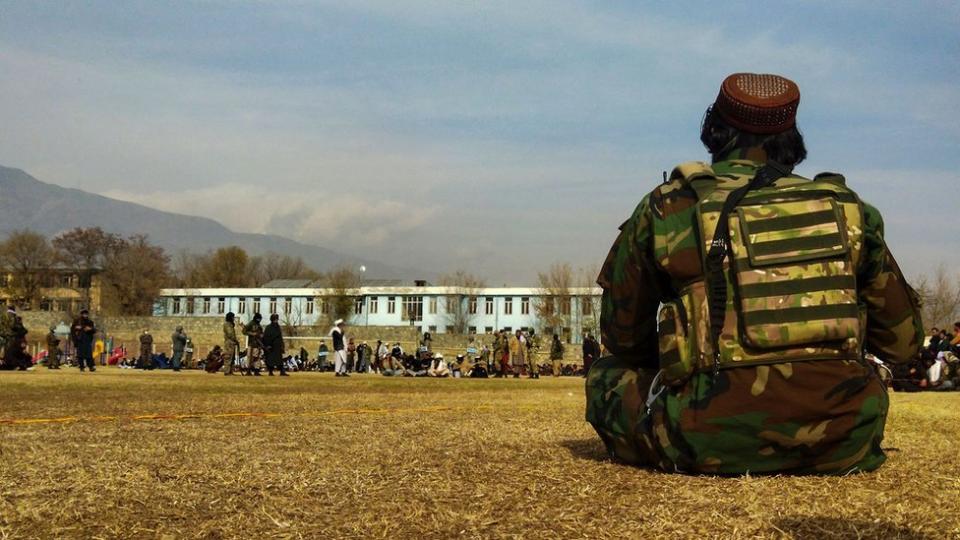 阿富汗帕爾旺省恰裏卡爾市一場公開體罰大會上一名塔利班戰鬥人員坐在草坪上（8/12/2022）