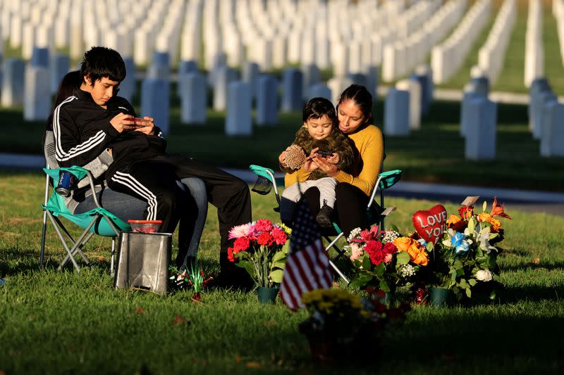 FILE PHOTO: Karina Hernandez, 35, sits with her one-year-old son Matthew, in front of the grave of her sister, U.S. Army Specialist Rocio Hernandez, at Los Angeles National Cemetery on Veterans’ Day