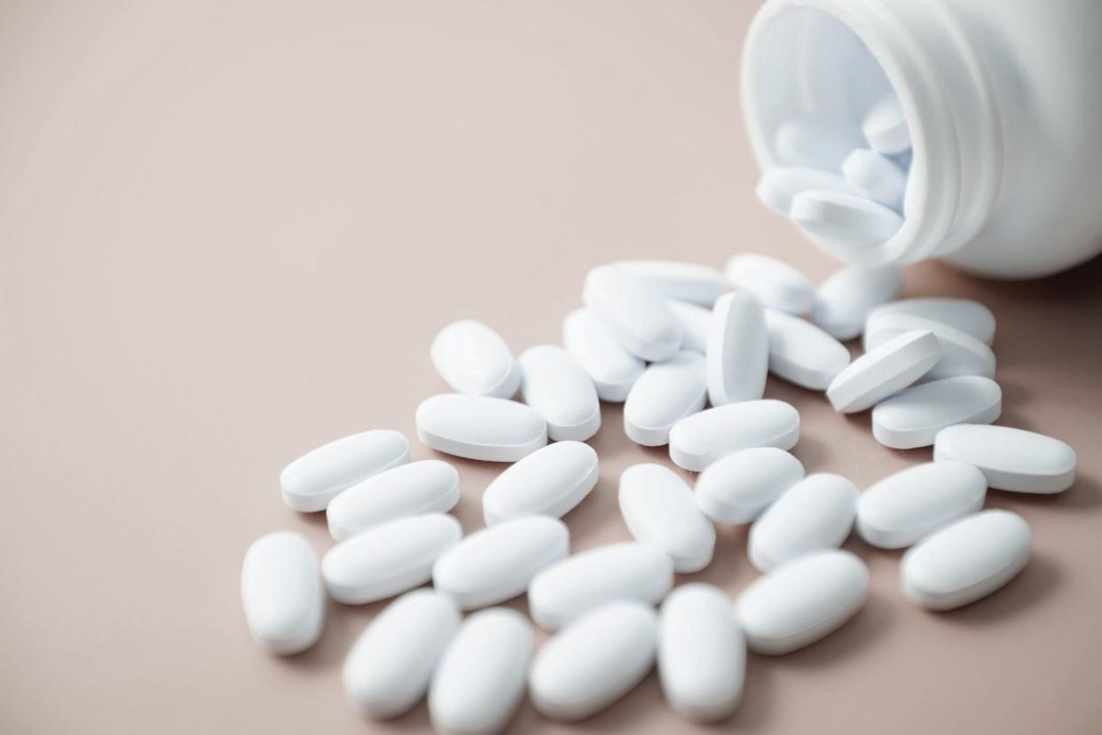 white calcium pills and pill bottle on neutral background