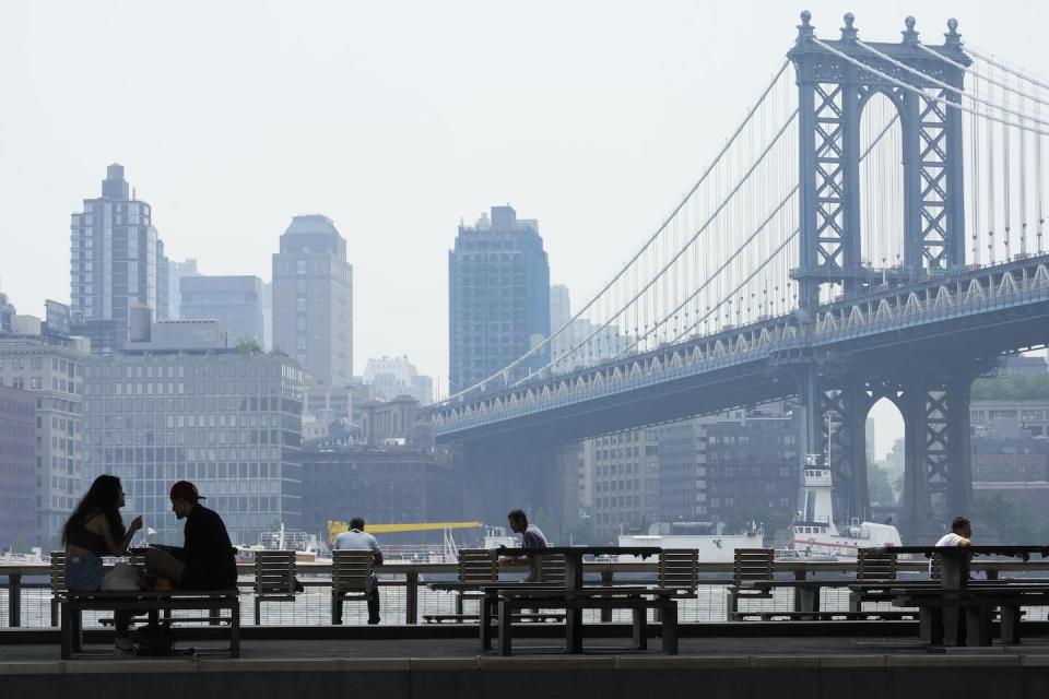 People on the East River promenade are framed by the hazy Brooklyn waterfront skyline and the Manhattan bridge on June 8 in New York. Smoke from Canadian wildfires is affecting air quality in some of the most densely populated areas of North America. (AP Photo/Mary Altaffer)