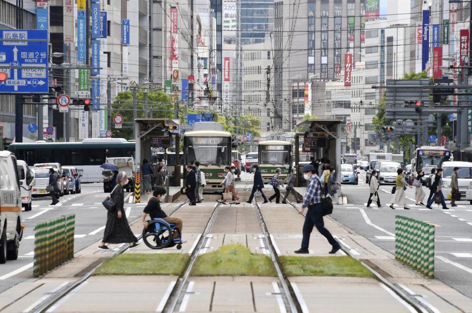 People wearing face masks make their way in Hiroshima, western Japan, Friday, May 14, 2021. Japan is set to further expand a coronavirus state of emergency, currently in Tokyo and five other prefectures, to nine areas, including HIroshima, as the government is determined to hold the Olympics in just over two months. (Shingo Nishizume/Kyodo News via AP)