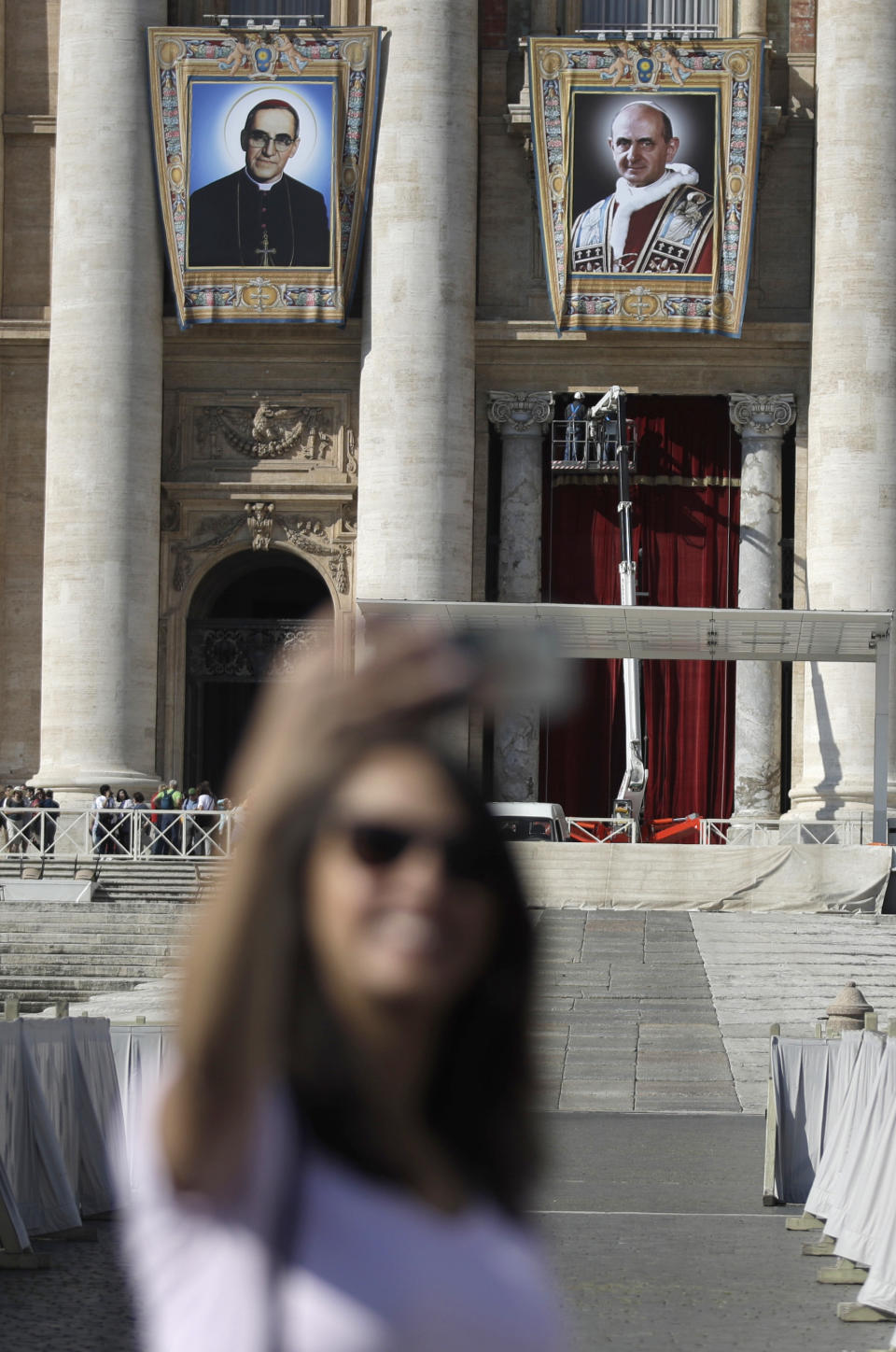 FILE - In this Friday, Oct. 12, 2018 filer, the tapestries of Roman Catholic Archbishop Oscar Romero, left, and Pope Paul VI hang from a balcony of the facade of St. Peter's Basilica at the Vatican. Pope Francis will canonize two of the most important and contested figures of the 20th-century Catholic Church, declaring Pope Paul VI and the martyred Salvadoran Archbishop Oscar Romero as models of saintliness for the faithful today. Sunday's ceremony is likely to be emotional for Francis, since he was greatly influenced by both men and privately told confidantes he wanted them made saints during his papacy. (AP Photo/Alessandra Tarantino, File )