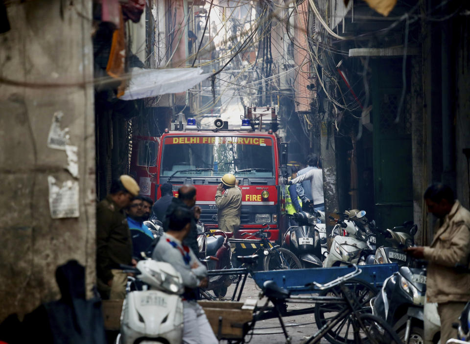 A fire engine stands by the site of a fire in an alleyway, tangled in electrical wire and too narrow for vehicles to access, in New Delhi, India, Sunday, Dec. 8, 2019. Dozens of people died on Sunday in a devastating fire at a building in a crowded grains market area in central New Delhi, police said. (AP Photo/Manish Swarup)