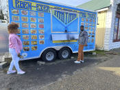 Clemene Bastien and Theslet Benoir stand outside of their Eben-Ezer Haitian food truck in Parksley, Va., on Wednesday, Jan. 24, 2024. The married couple is suing the town in federal court over allegations that their food truck was forced to close. The couple also says a town councilman cut the mobile kitchen's water line and screamed, "Go back to your own country!" (AP Photo/Ben Finley)