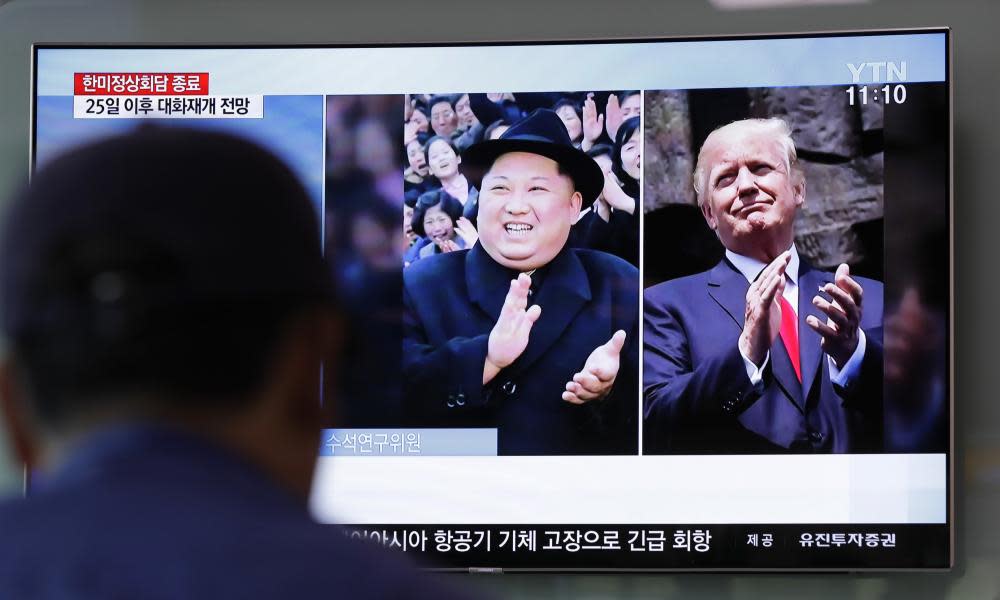 A man watches a TV screen showing file footage of U.S. President Donald Trump, right, and North Korean leader Kim Jong Un 