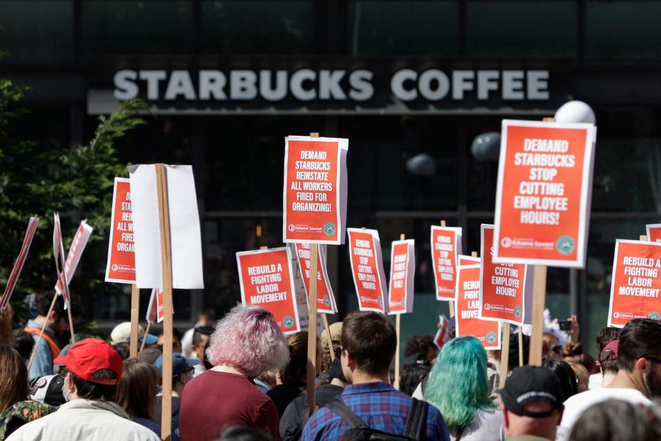 A Starbucks Coffee shop is seen in the background as people gather at Westlake Park during the "Fight Starbucks' Union Busting" rally and march in Seattle, Washington on April 23, 2022.