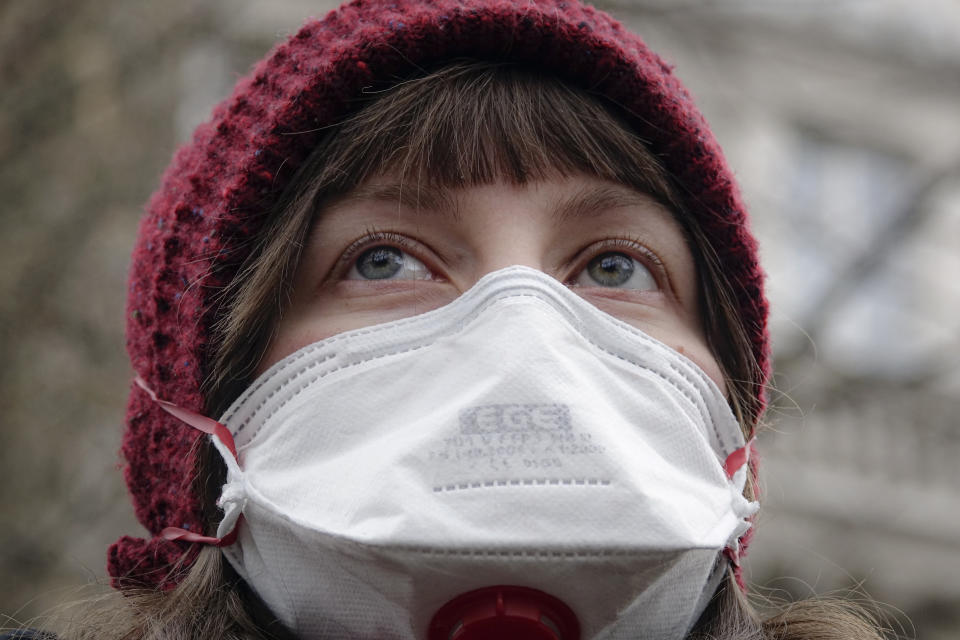 A woman wearing a gas mask takes part in a protest against air pollution, in Sarajevo, Bosnia, Monday, Jan. 20, 2020. Dozens of people, some wearing face masks, gathered for a protest because of dangerously high levels of air pollution in the past weeks in the Bosnian capital after measurements in the past weeks have shown that levels of damaging airborne particles have exceeded European Union's safety norms by several times.(AP Photo/Eldar Emric)