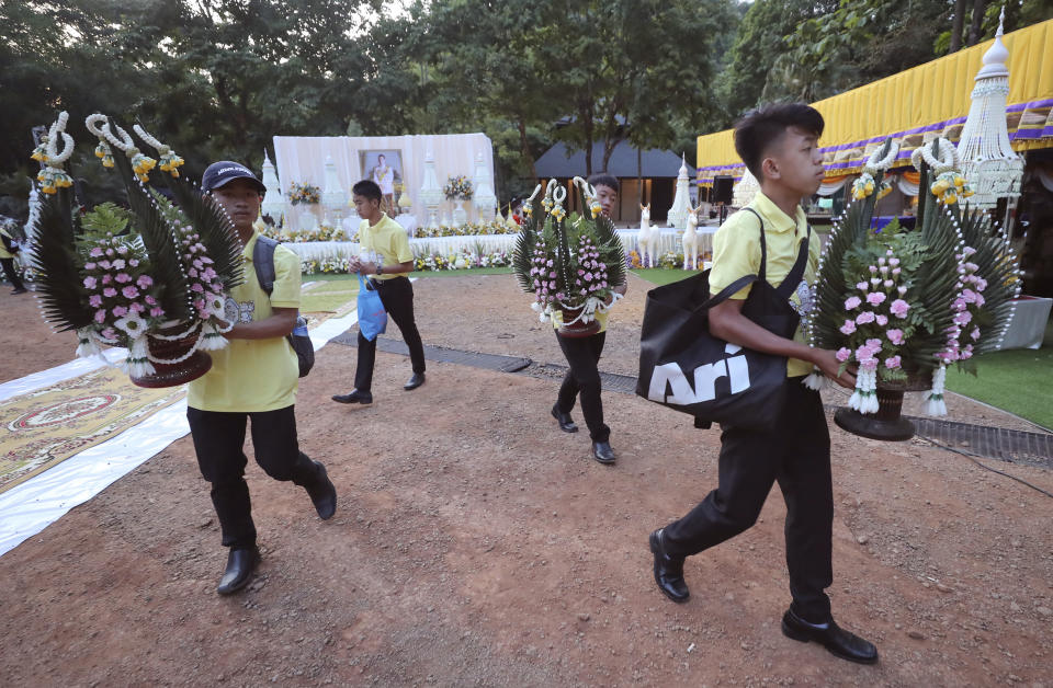 Members of the Wild Boars soccer team who were rescued from a flooded cave, carry flowers for a religious ceremony near the Tham Luang cave in Mae Sai, Chiang Rai province, Thailand Monday, June 24, 2019. The 12 boys and their coach attended a Buddhist merit-making ceremony at the Tham Luang to commemorate the one-year anniversary of their ordeal that saw them trapped in a flooded cave for more than two weeks. (AP Photo/Sakchai Lalit)