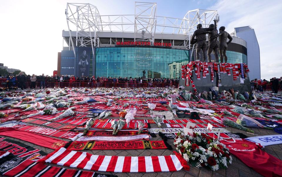 Scarves are placed around the statue of Best, Charlton and Law