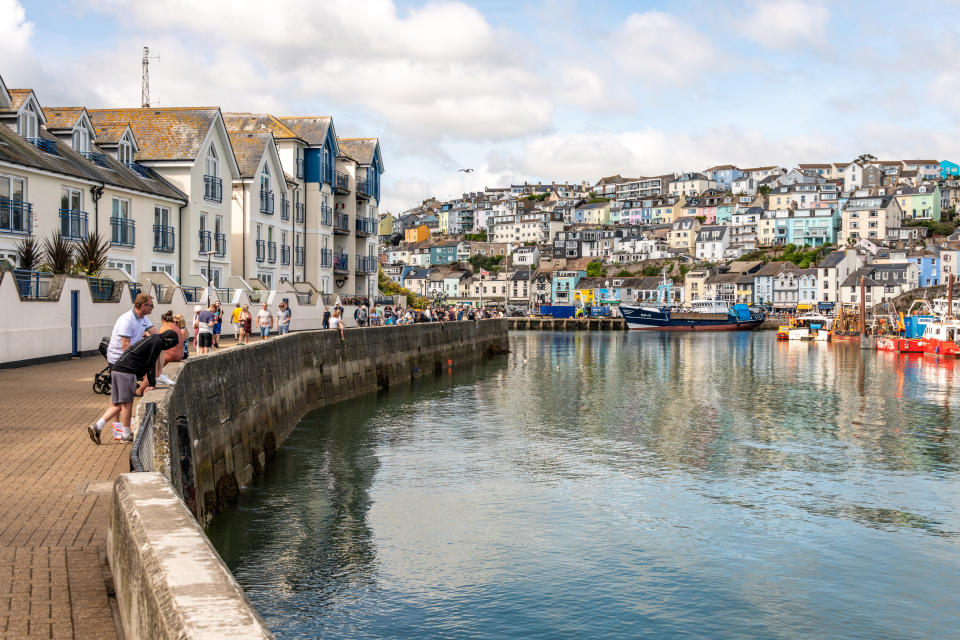 seaside  Brixham, UK. 10 August 2021. A variety of tourists on the quayside in Brixham Harbour in Devon.