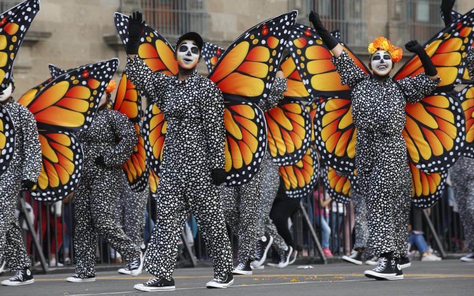 Performers in monarch butterfly costumes wave to the crowd as they walk in a Day of the Dead parade in Mexico City, Sunday, Oct. 27, 2019. The parade on Sunday marks the fourth consecutive year that the city has borrowed props from the opening scene of the James Bond film, "Spectre," in which Daniel Craig's title character dons a skull mask as he makes his way through a crowd of revelers. (AP Photo/Ginnette Riquelme)