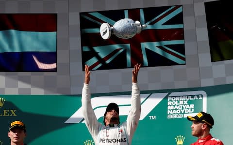 Hungarian Grand Prix - Hungaroring, Budapest, Hungary - August 4, 2019 Mercedes' Lewis Hamilton celebrates winning the Hungarian Grand Prix on the podium with his trophy while Red Bull's Max Verstappen and Ferrari's Sebastian Vettel look on - Credit: REUTERS