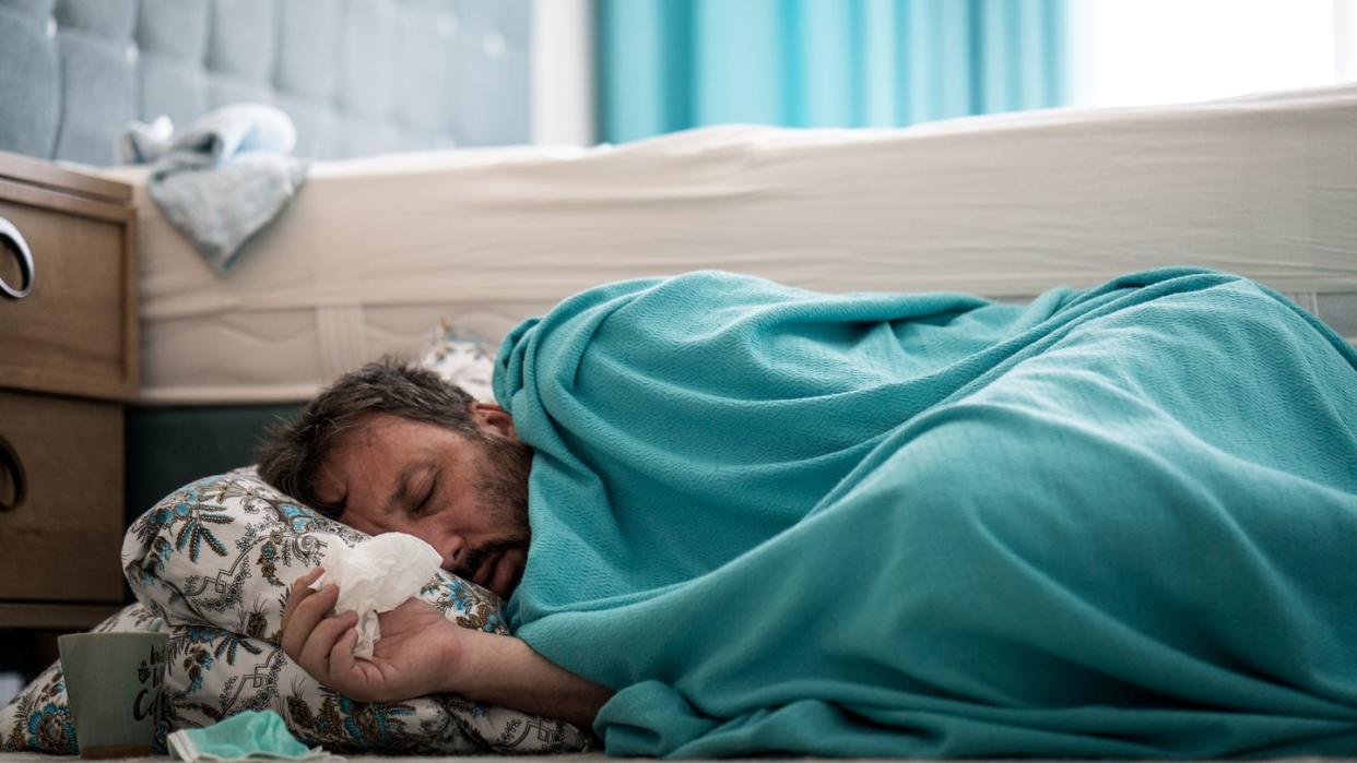 sick man with fever on ground in bedroom