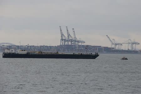 A barge is seen in the harbor of New York during a work stoppage at New Jersey ports, pictured in the background, January 29, 2016. REUTERS/Brendan McDermid