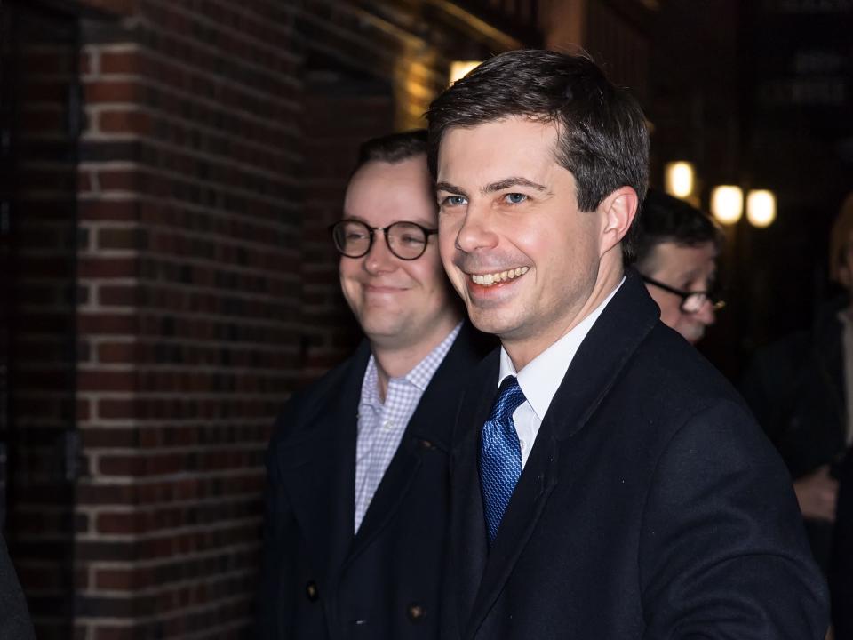 chasten and pete in suits smiling at camera