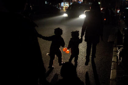 Two children dressed in their Halloween costumes hold pumpkin-shaped lanterns while walking on their way to ask for candies from neighbors the night before Halloween in Beijing, China, Wednesday, Oct. 30, 2013. (AP Photo/Alexander F. Yuan)