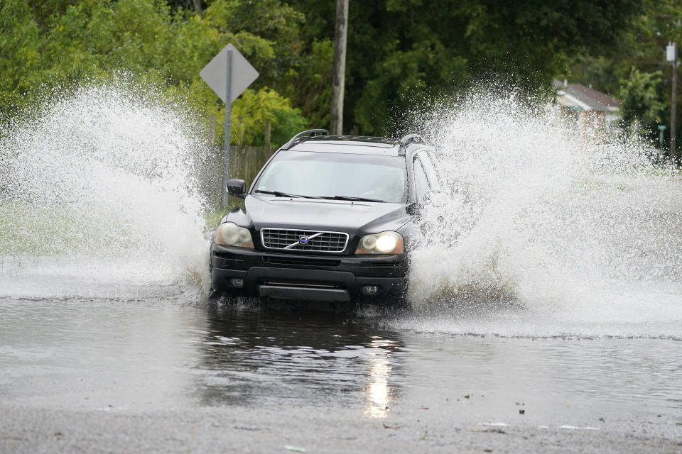 A vehicle splashes runoff water from Tropical Storm Claudette, Saturday, June 19, 2021, in downtown Biloxi, Miss. Although flooding was minor in this neighborhood, some drivers encountered pools they needed to drive through. (AP Photo/Rogelio V. Solis)