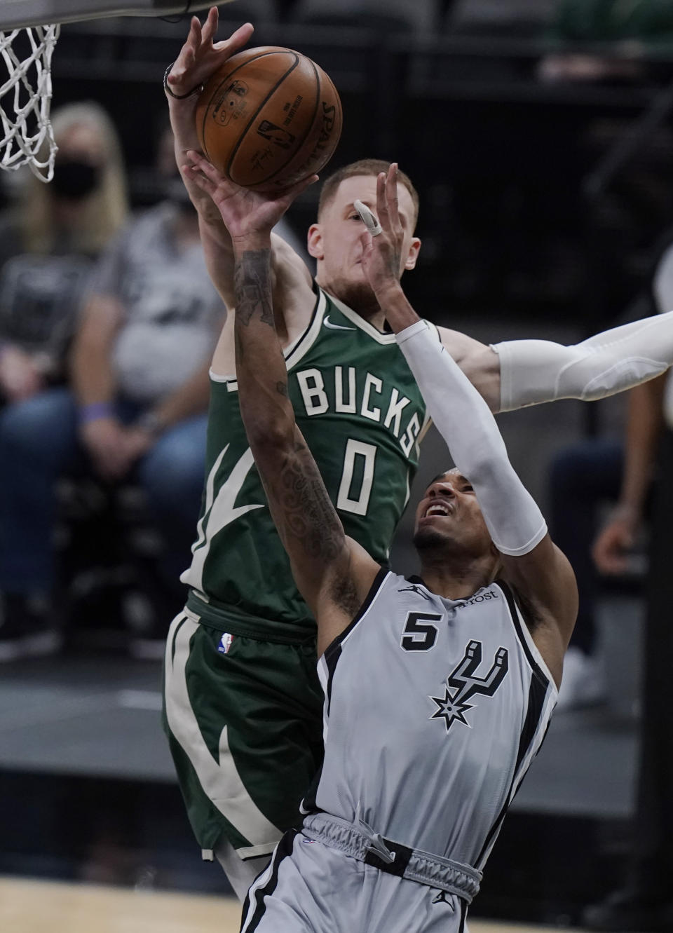 San Antonio Spurs guard Dejounte Murray (5) is blocked by Milwaukee Bucks guard Donte DiVincenzo (0) as he tries to score during the second half of an NBA basketball game in San Antonio, Monday, May 10, 2021. (AP Photo/Eric Gay)