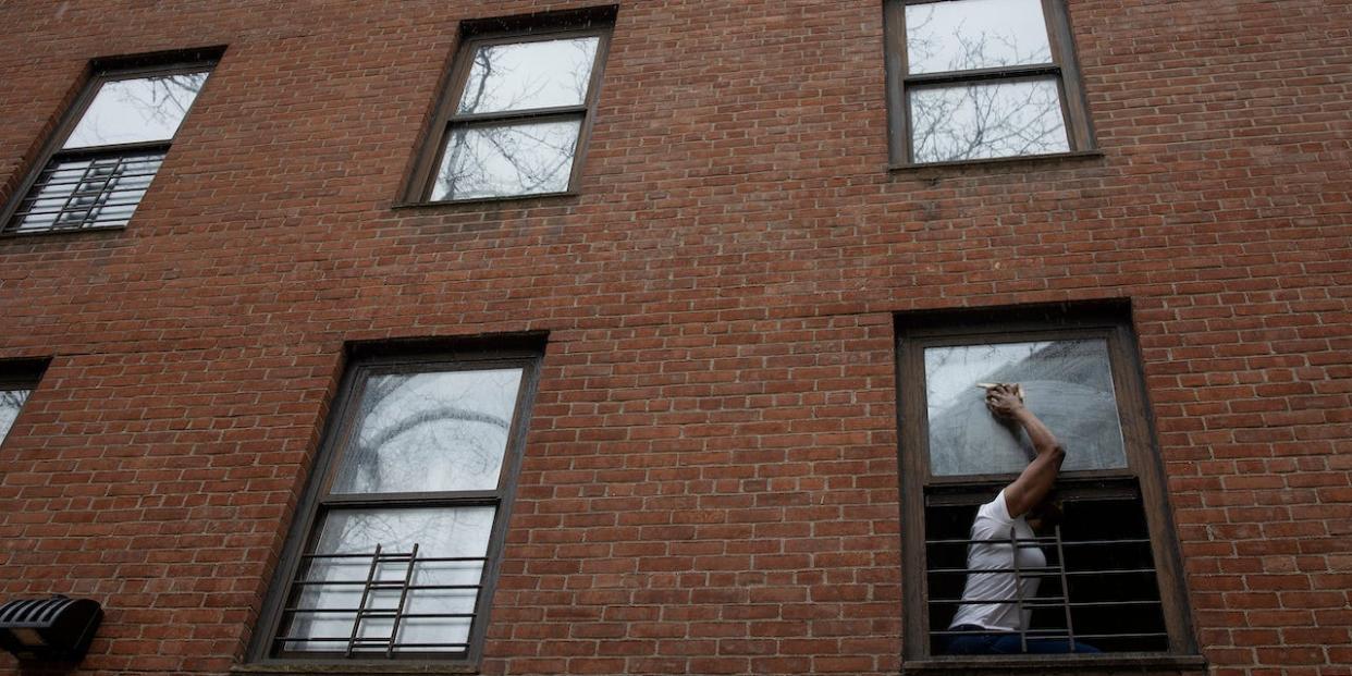 A woman cleans the windows of her apartment in a public housing complex on April 12, 2022 in the Lower East Side neighborhood of New York City, New York.