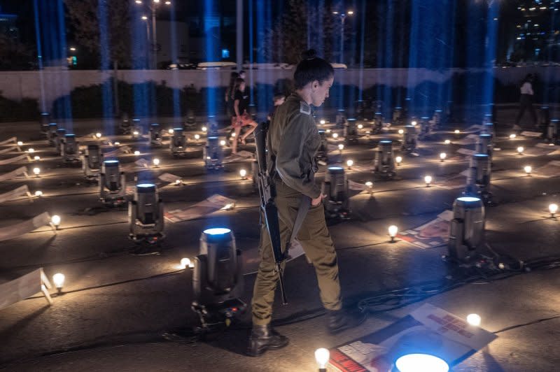 An armed Israeli soldier looks at the posters of some of the 229 Israelis held hostage by Hamas inside the Gaza Strip in a nightly vigil held outside a sports stadium n southern Jerusalem on Sunday. Photo by Jim Hollander/UPI