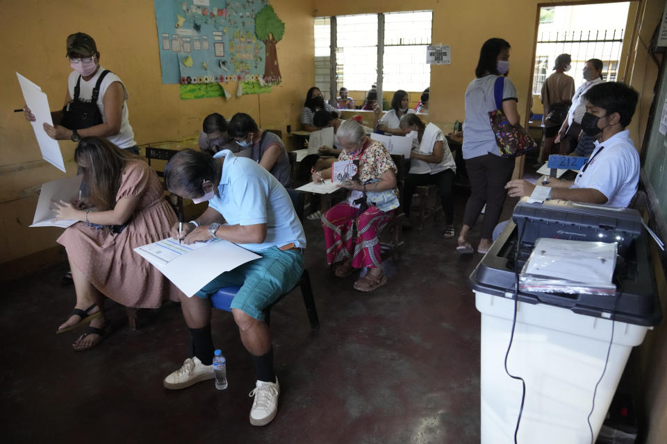 People vote at a school used as a polling center Monday, May 9, 2022 in Quezon City, Philippines. Filipinos were voting for a new president Monday, with the son of an ousted dictator and a champion of reforms and human rights as top contenders in a tenuous moment in a deeply divided Asian democracy. (AP Photo/Aaron Favila)