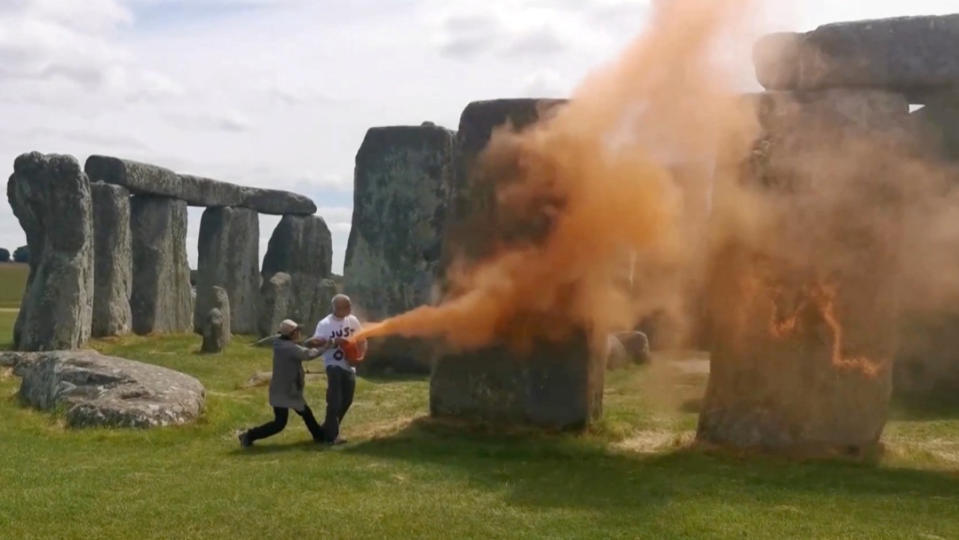 2024年6月19日，環保團體「攔住石油」成員朝英國巨石陣噴橘色粉末塗料，一名遊客（穿外套者）上前攔阻。路透社