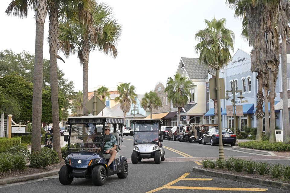 FILE - Residents drive golf carts through the Lake Sumter Landing Market Square on Aug. 12, 2021, in The Villages, Fla. Sumter County, Florida, home of the booming retirement community, The Villages, had the highest median age at 68.5, while Utah County, home to Provo, Utah, had the lowest at 25.9. (AP Photo/Phelan M. Ebenhack, File)