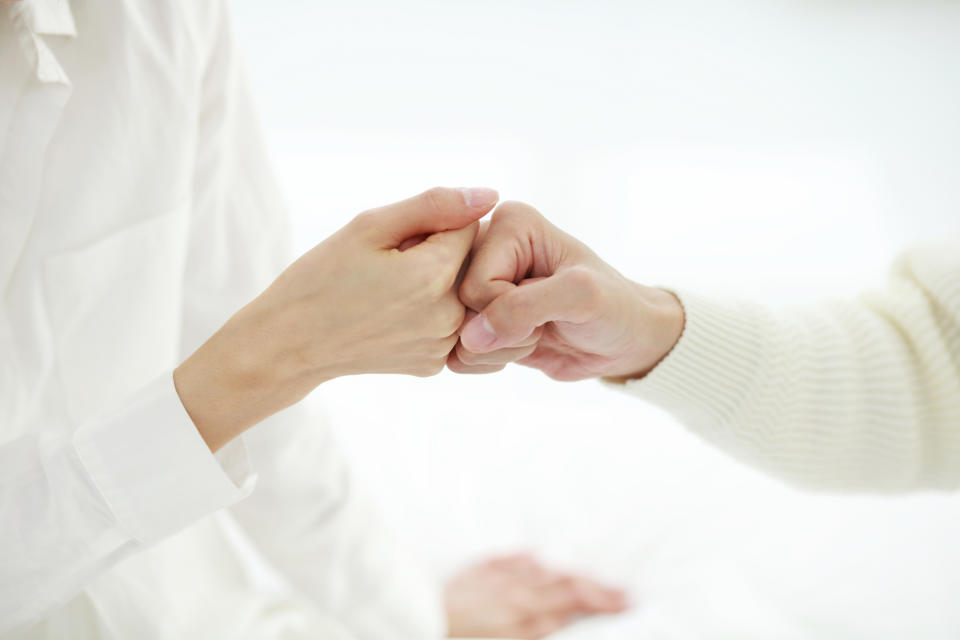 Two people gently touching fists, a gesture often signifying unity or support. Their hands and part of their forearms are visible