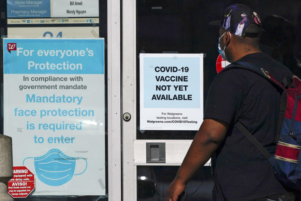 FILE - In this Dec. 2, 2020, file photo, a customer walks past a sign indicating that a COVID-19 vaccine is not yet available at Walgreens in Long Beach, Calif. (AP Photo/Ashley Landis, File)