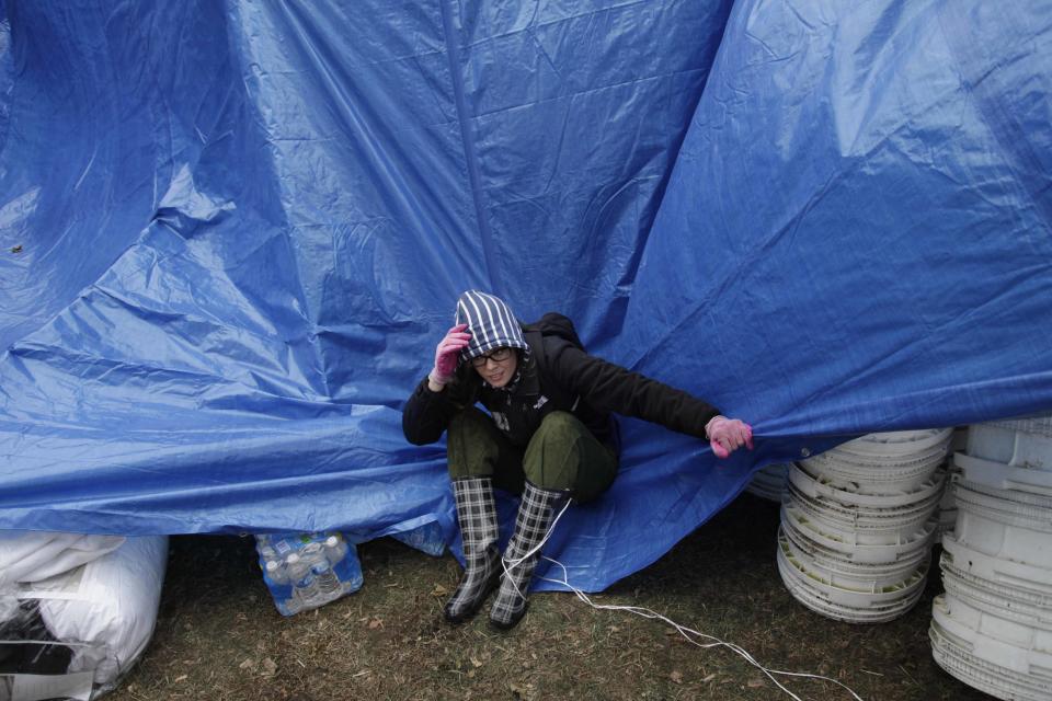 Gina Kohm tries to keep a tarp from blowing away which covers a pile of donated supplies at an aid station in the New Dorp section of Staten Island, New York, Wednesday, Nov. 7, 2012.  Residents of New York and New Jersey who were flooded out by Superstorm Sandy are waiting with dread Wednesday for the second time in two weeks as another, weaker storm heads toward them and threatens to inundate their homes again or simply leave them shivering in the dark for even longer. (AP Photo/Seth Wenig)