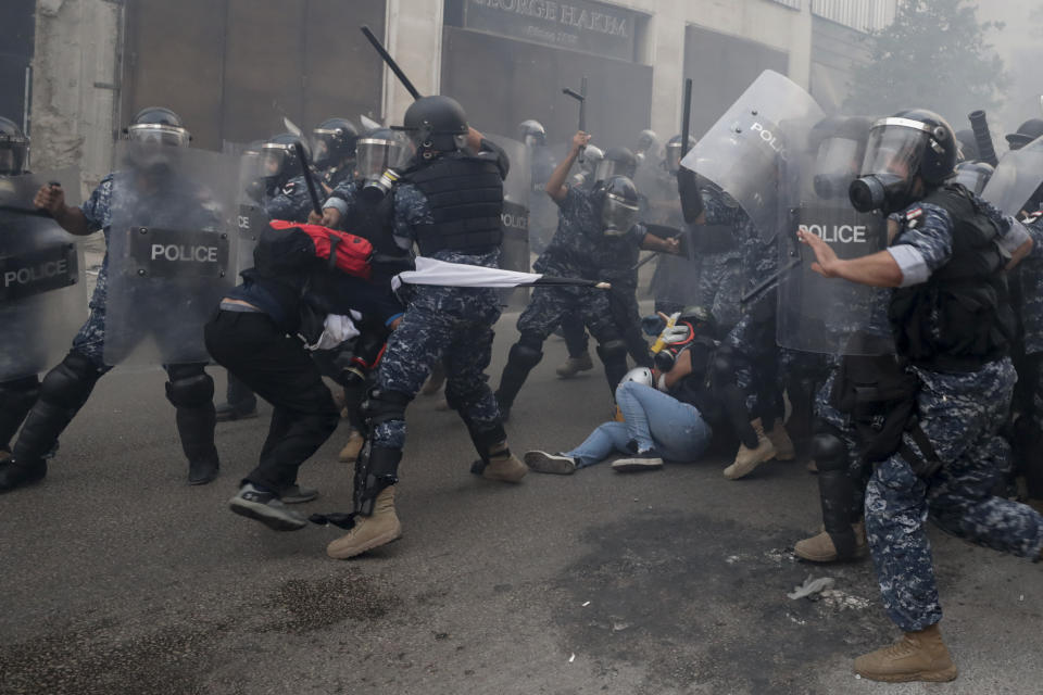 Riot policemen beat anti-government protesters during a protest near Parliament Square, in Beirut, Lebanon, Tuesday, Sept. 1, 2020. On a visit to Lebanon, French President Emmanuel Macron issued a stern warning to Lebanon's political class Tuesday, urging them to commit to serious reforms within a few months or risk punitive action, including sanctions, if they fail to deliver. (AP Photo/Hassan Ammar)